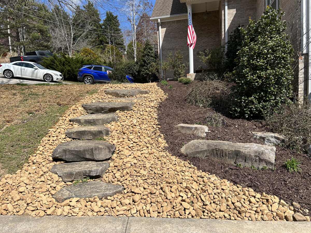 Finished river-rock walkway with set stone steppers and fresh mulch beds
